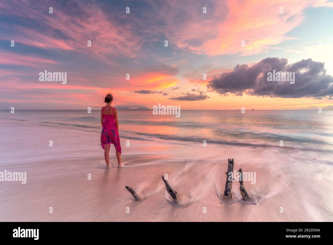 Donna sulla spiaggia tropicale guarda il mare dei Caraibi al tramonto Foto Stock