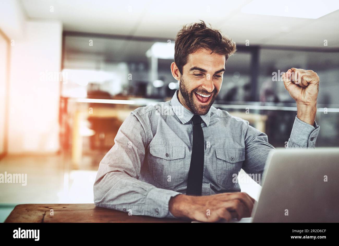 Uomo d'affari, pugno e festeggiamenti con notebook, vincita o promozione all'avvio con il volto eccitato. Giovane uomo d'affari, vincitore e festeggia con Foto Stock