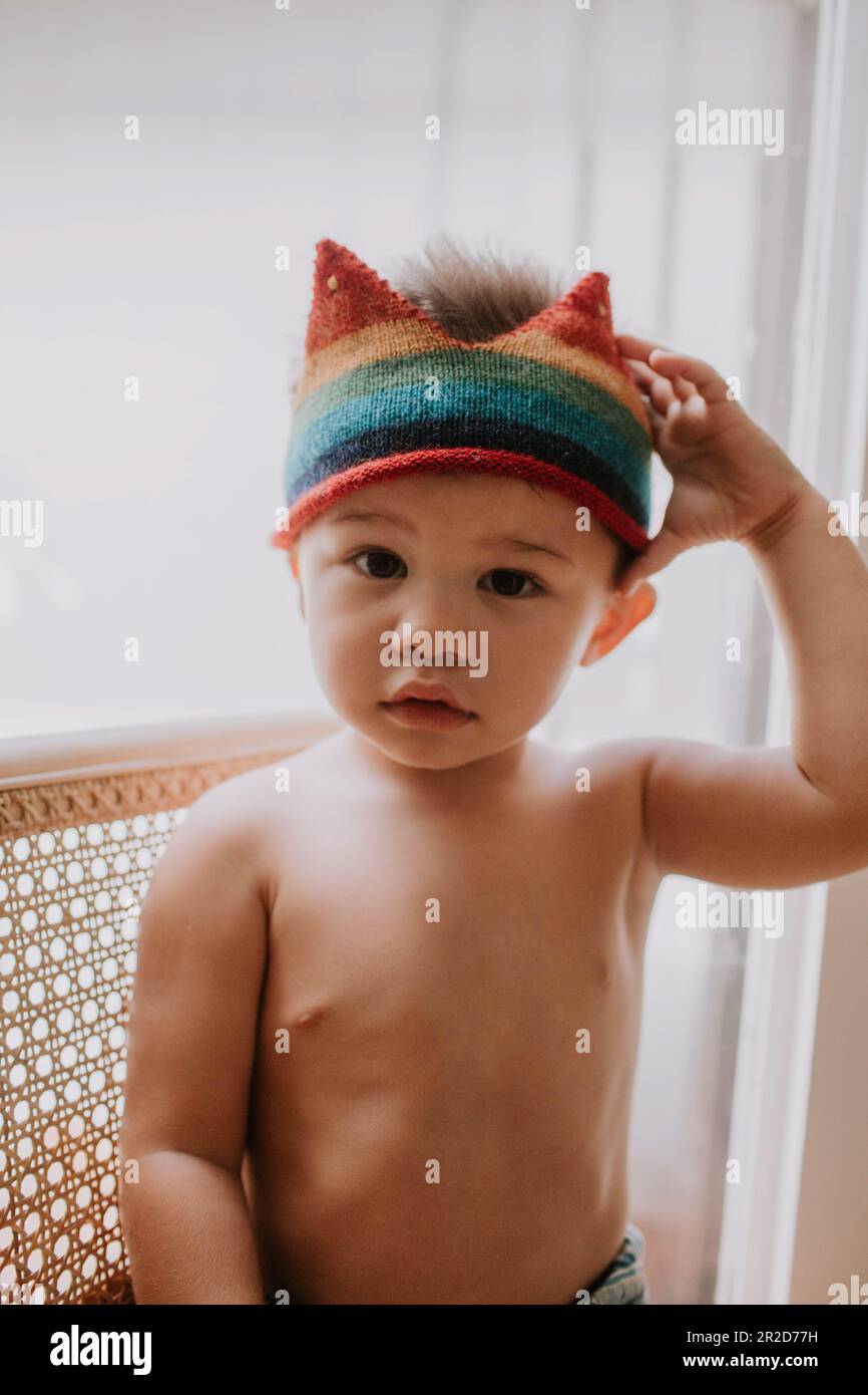 Bambino seduto su una sedia che tocca la corona sulla sua testa. Foto Stock