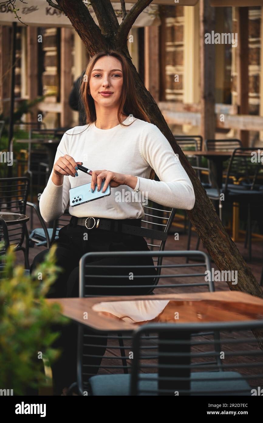 La bella ragazza bianca seduta nel caffè fuori Foto Stock