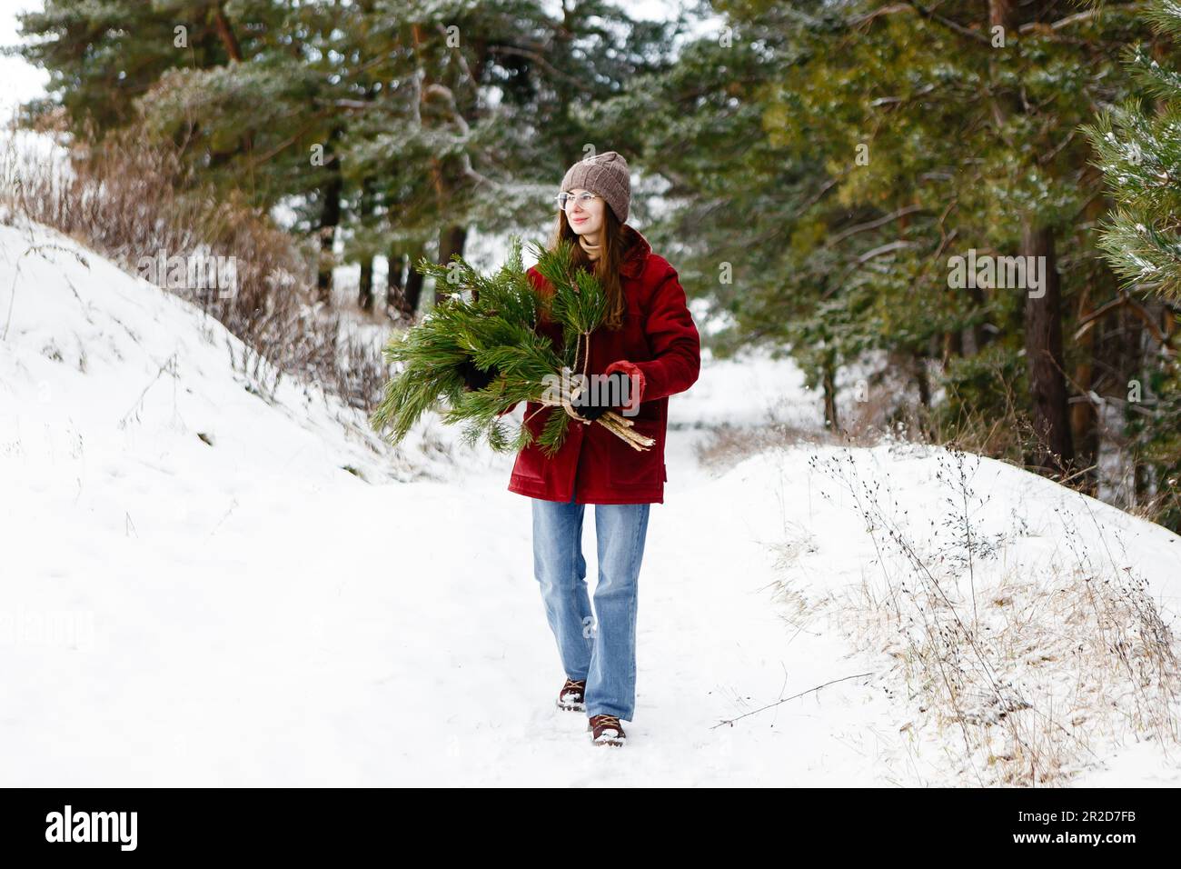 Donna con albero di Natale nelle sue mani in mezzo alla foresta invernale Foto Stock