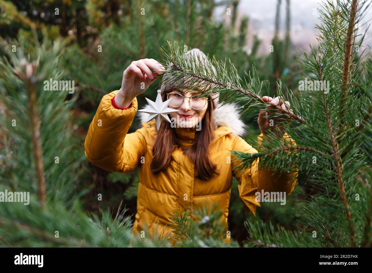 una giovane donna appende le decorazioni su un albero di natale Foto Stock