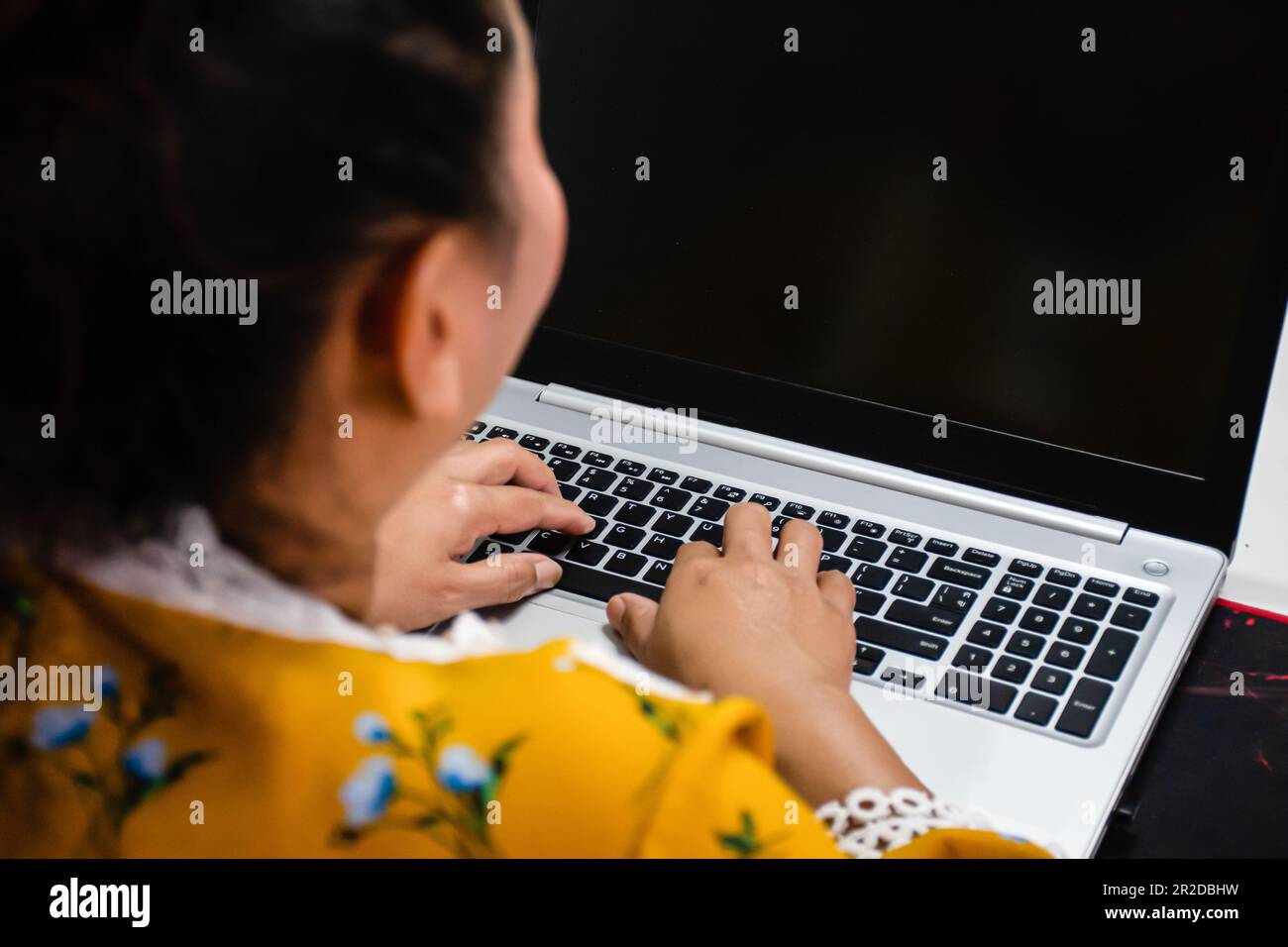 Una donna che utilizza un computer portatile con dati chiave per lavorare a casa scattando una foto ravvicinata del retro. Foto Stock