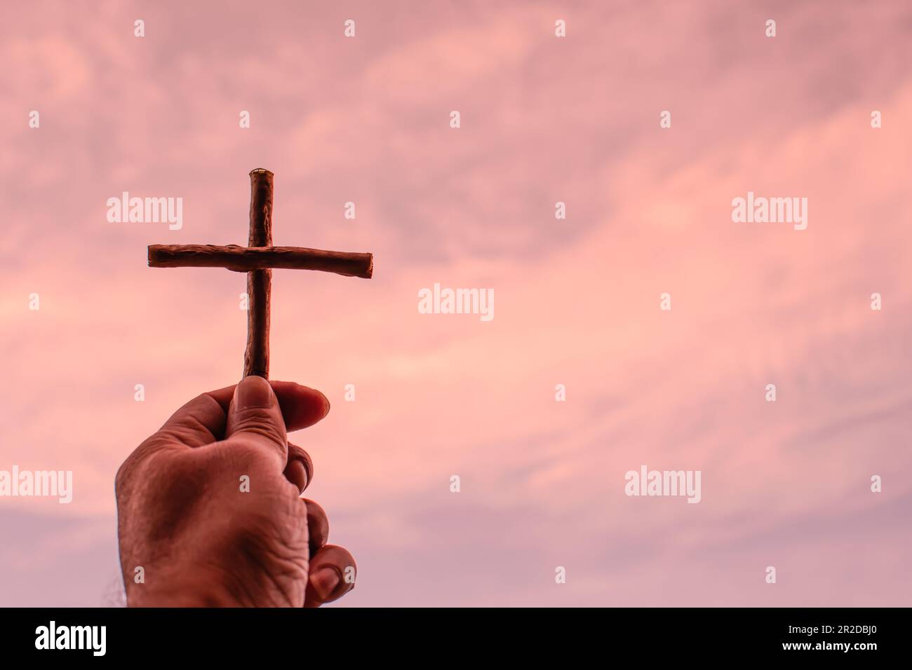 La sua croce di sostegno sinistra fino al cielo giallo dorato. Spazio copyspace sinistro per l'immissione del testo. Primo piano con nuvole sfocate in una bella giornata. Foto Stock