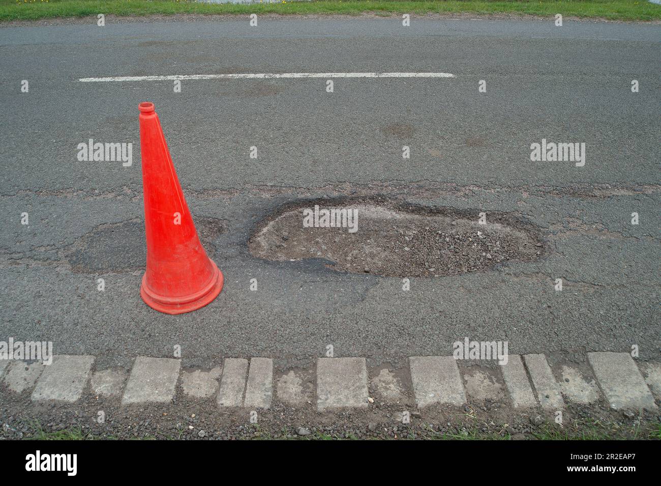 Dorney, Buckinghamshire, Regno Unito. 19th maggio, 2023. Anche se alcuni buche sono state patched nel vicino villaggio rurale di Dorney REACH nel Buckinghamshire oggi, ci sono ancora un certo numero di buche sulla strada comune nel Dorney Village che hanno ancora bisogno di riparare. Questo ha un cono di avvertimento da esso ma continua ad essere bussato sopra passando il traffico. Buckinghamshire ha migliaia di buche non riparate che vengono lentamente applicate con una nuova macchina Velocity Patcher. Credit: Maureen McLean/Alamy Live News Foto Stock