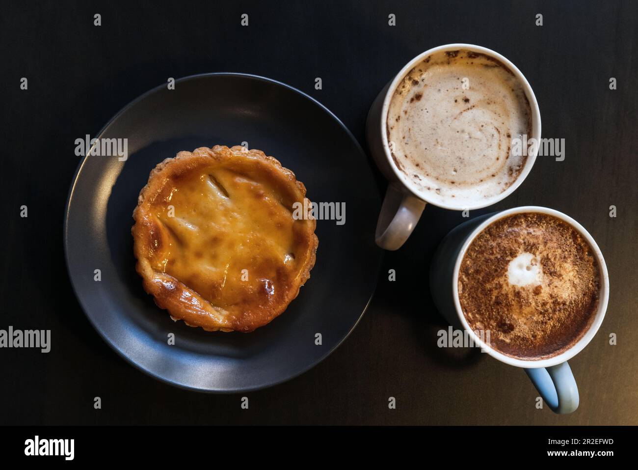 Pastello de nata e due tazze di caffè cappuccino, vista dall'alto Foto Stock