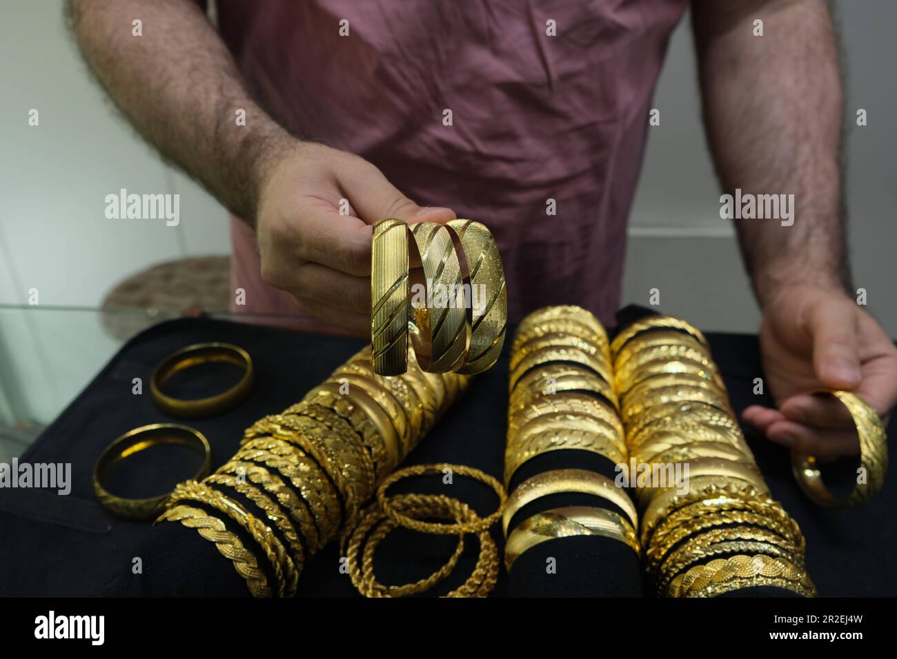 Il venditore mostra tre braccialetti dorati in un negozio di gioielli in Turchia. Foto Stock