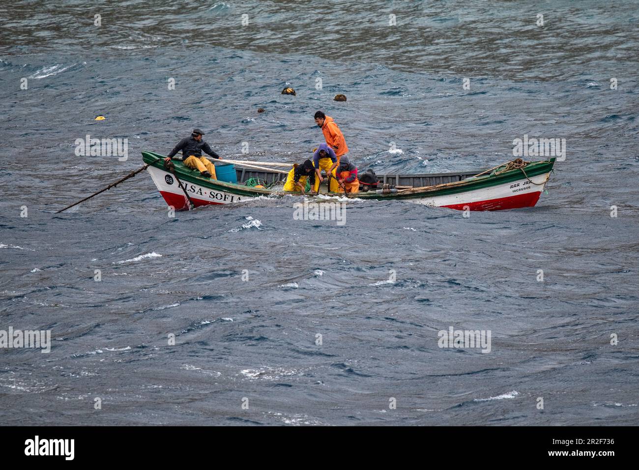 Una piccola barca da pesca dall'isola sfida i mari accidentati per avvicinarsi a una nave da crociera di spedizione in visita, l'isola Alejandro Selkirk, le isole Juan Fernández Foto Stock