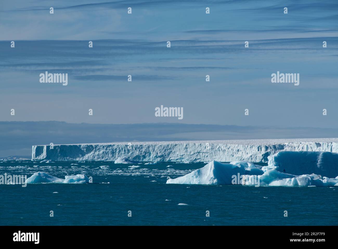 Una scena di iceberg sciolti e la lingua della calotta di ghiaccio Austfonna sotto un cielo poco nuvoloso, Brasvellbreena, Nordaustlandet, Spitsbergen, Norvegia, Euro Foto Stock