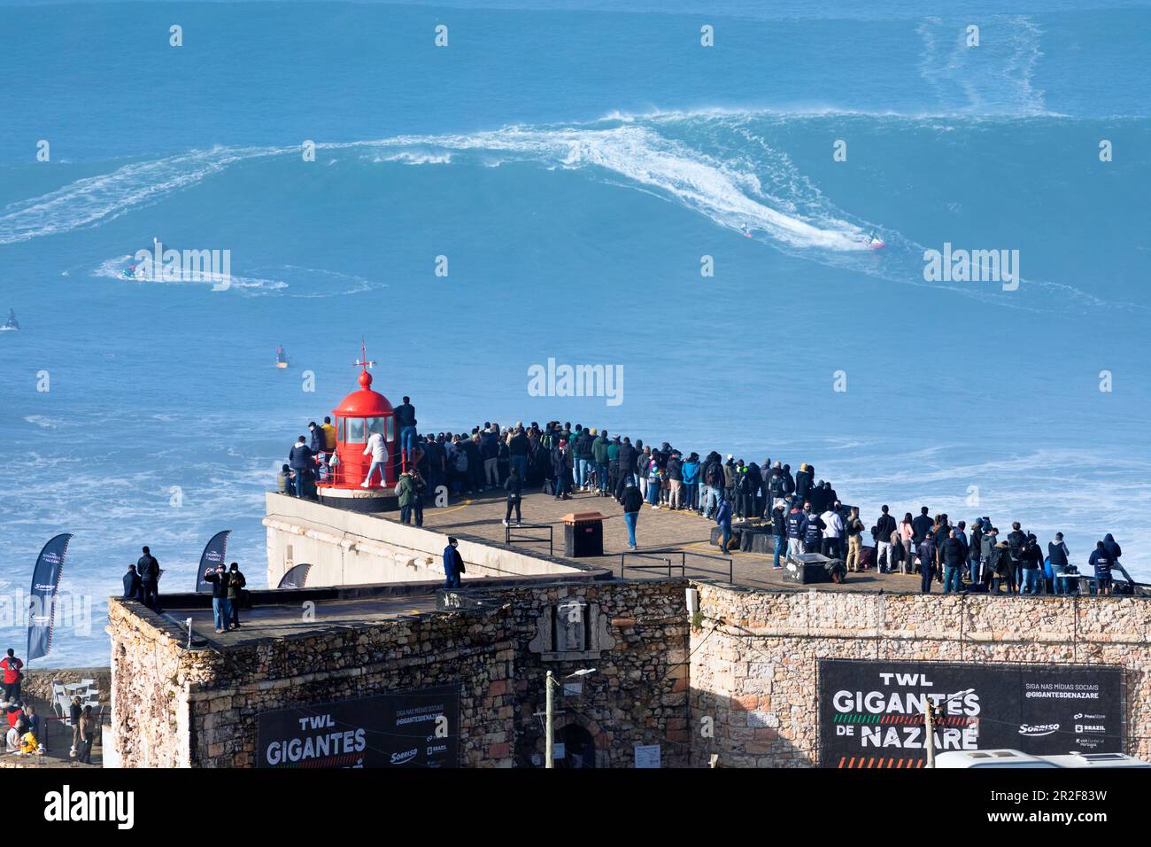 Europa, Portogallo, Regione di Oeste, Nazaré, Surfer e supporto Jet ski cavalcando onde enormi vicino Praia do Norte durante il Free Surfing Event 2022 Foto Stock