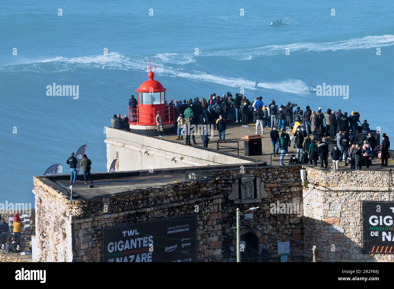 Europa, Portogallo, regione di Oeste, Nazaré, folla che guarda un Tow-Surfer in sella a onde enormi vicino Praia do Norte durante un evento nel gennaio 2022 Foto Stock