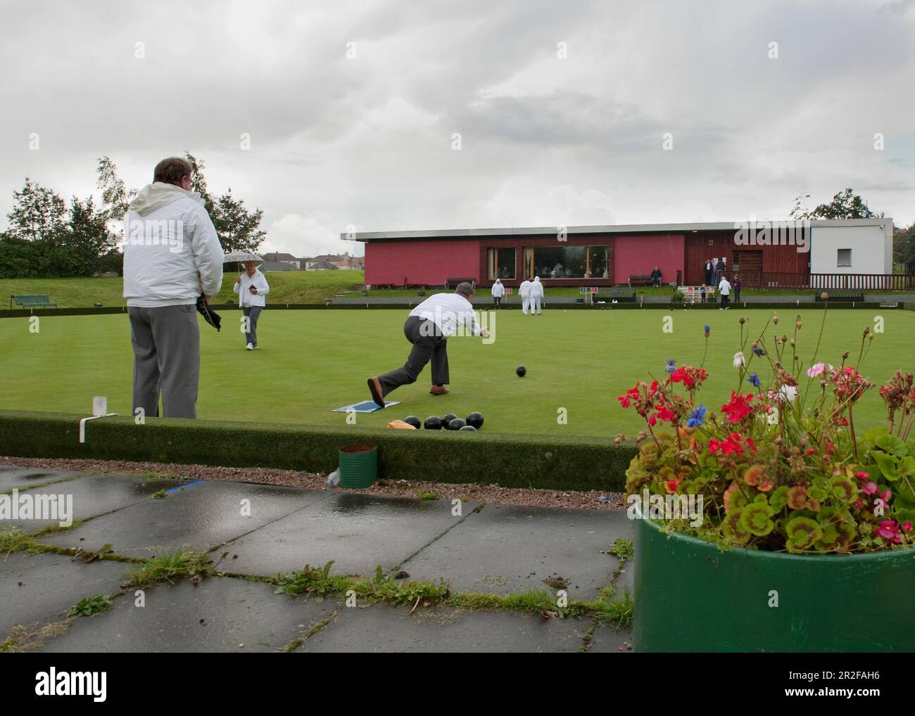 Bocce in gioco di fronte al circolo del padiglione rosso presso il campo da bowling Balornock a Glasgow, Scozia, Regno Unito Foto Stock