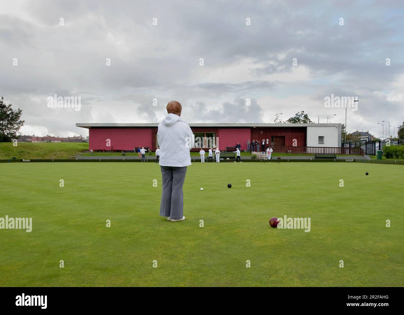 Bocce in gioco di fronte al circolo del padiglione rosso presso il campo da bowling Balornock a Glasgow, Scozia, Regno Unito Foto Stock