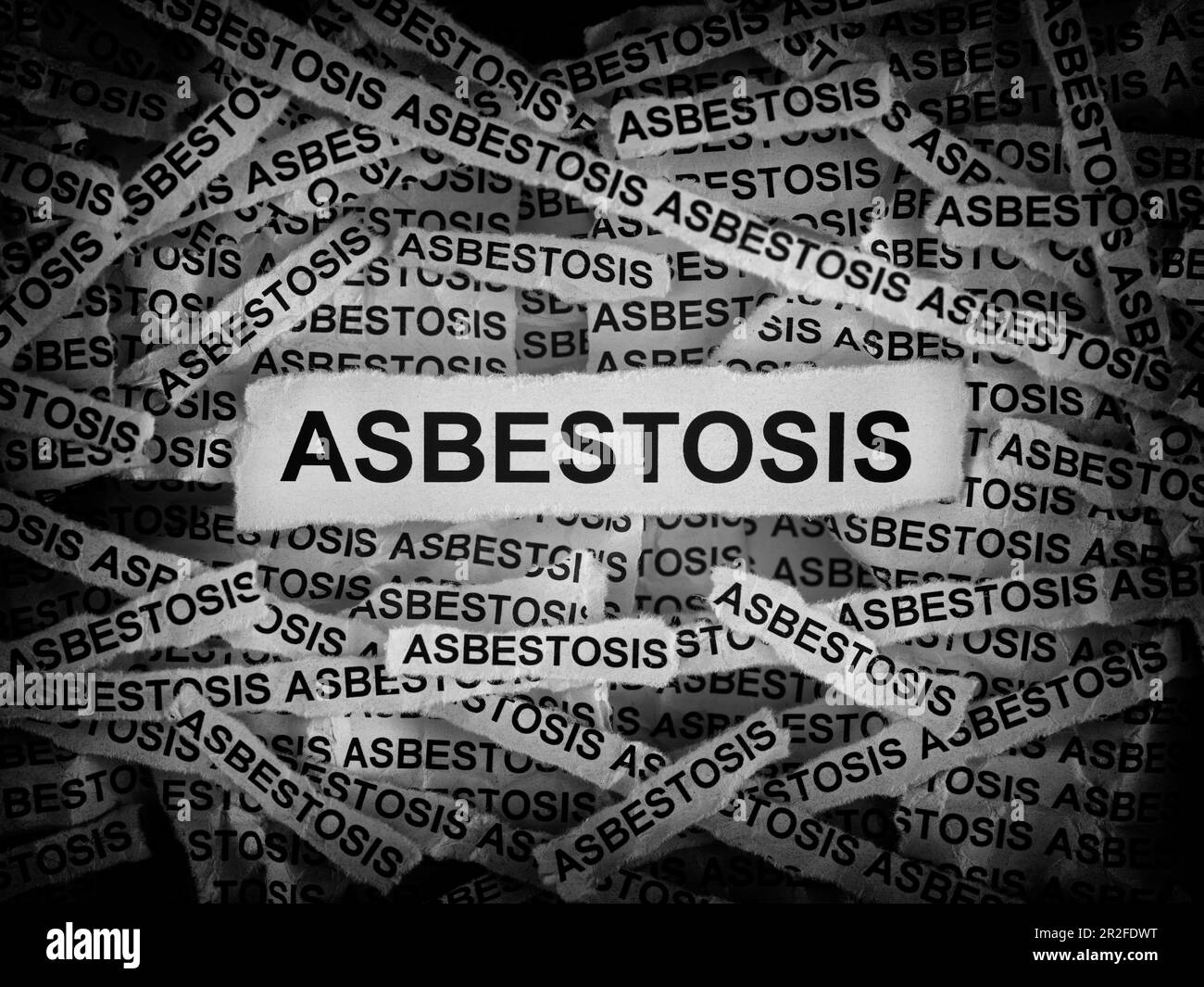 Strisce di giornale con la parola Asbestosis digitata su di loro. Bianco e nero. Primo piano. Foto Stock