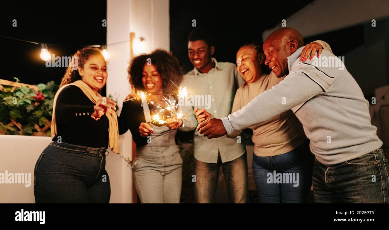Famiglia africana felice che festeggia con i fuochi d'artificio scintillanti alla festa della casa - genitori e concetto di festa Foto Stock