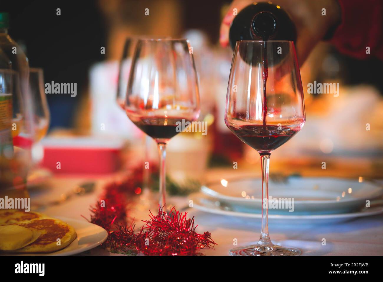 Vino rosso poring mano sul tavolo della cena di Natale Foto Stock