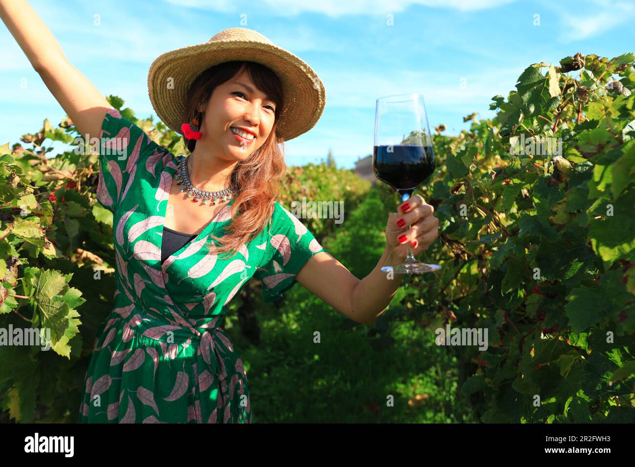 Donna asiatica felice tenuta vino rosso glasse a vigneto, concetto di celebrazione Foto Stock