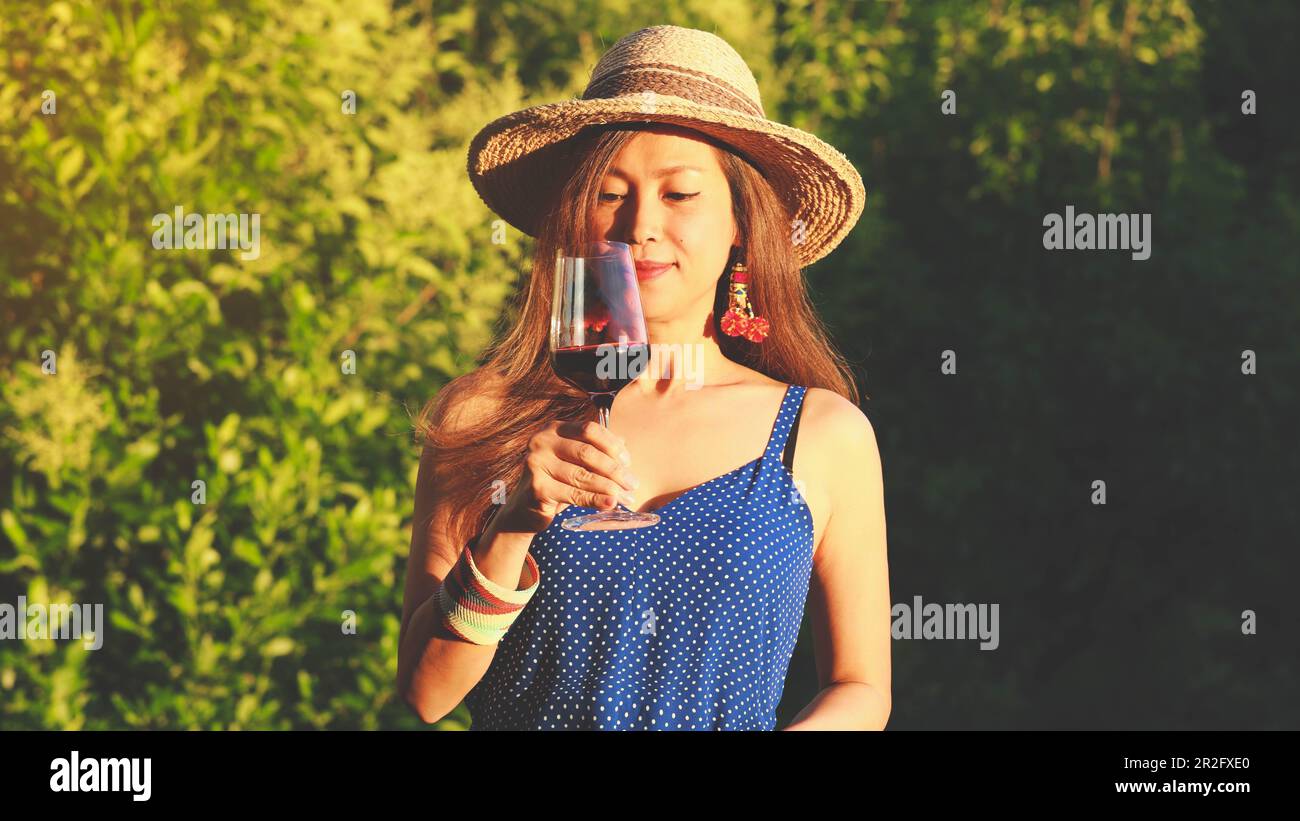 Felice donna asiatica bere vino rosso, concetto di festa Foto Stock