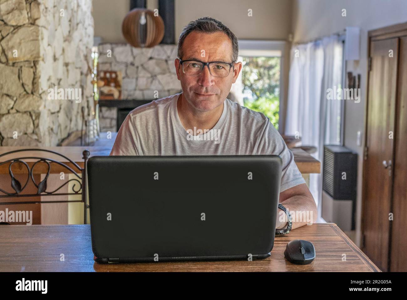 Ritratto di un buon uomo che lavora a casa su un progetto a un tavolo guardando la fotocamera Foto Stock