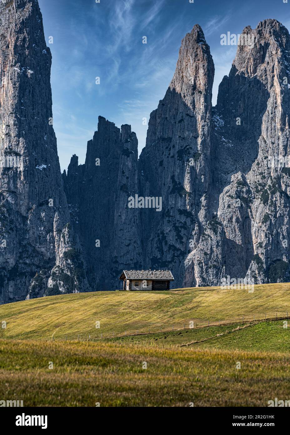 Rifugio solitario di fronte ad un massiccio muro di montagna sull'Alpe di Siusi in Alto Adige Foto Stock