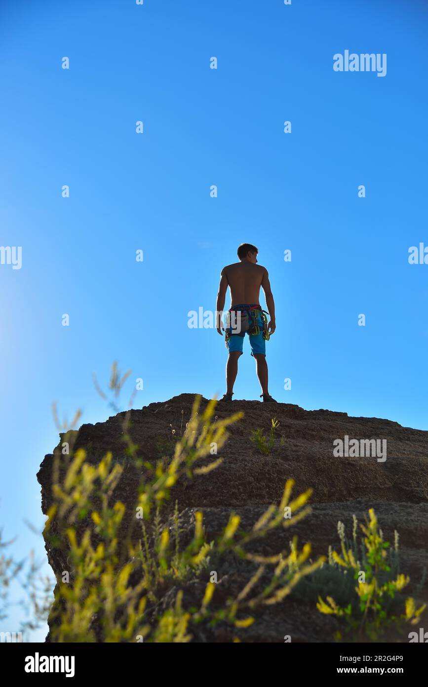 atletico uomo arrampicatore in piedi sulla cima della montagna Foto Stock