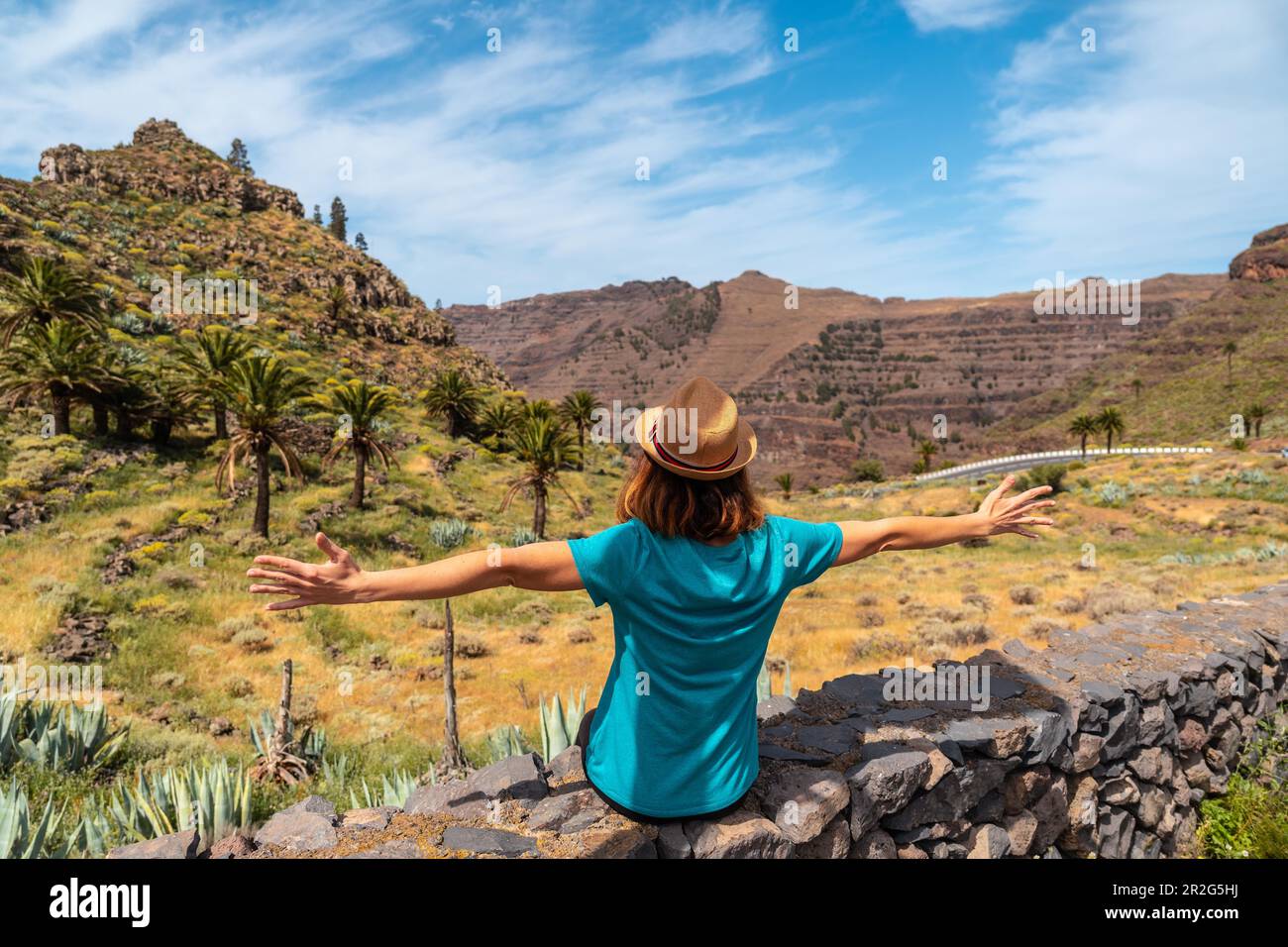 Un giovane turista con un cappello seduto sul punto di vista di El Palmarejo a la Gomera, Isole Canarie Foto Stock