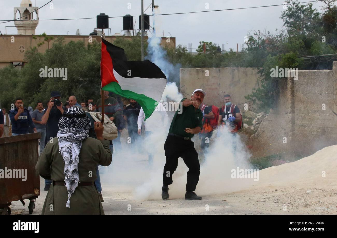 Kufr Qadoom, Nablus. 19th maggio, 2023. Un manifestante palestinese lancia un barattolo di gas lacrimogeno sparato da un soldato israeliano durante gli scontri a seguito di una protesta contro l'espansione degli insediamenti ebrei nel villaggio di Kufr Qadoom, vicino a Nablus, il 19 maggio 2023. Credit: Nidal Eshtayeh/Xinhua/Alamy Live News Foto Stock