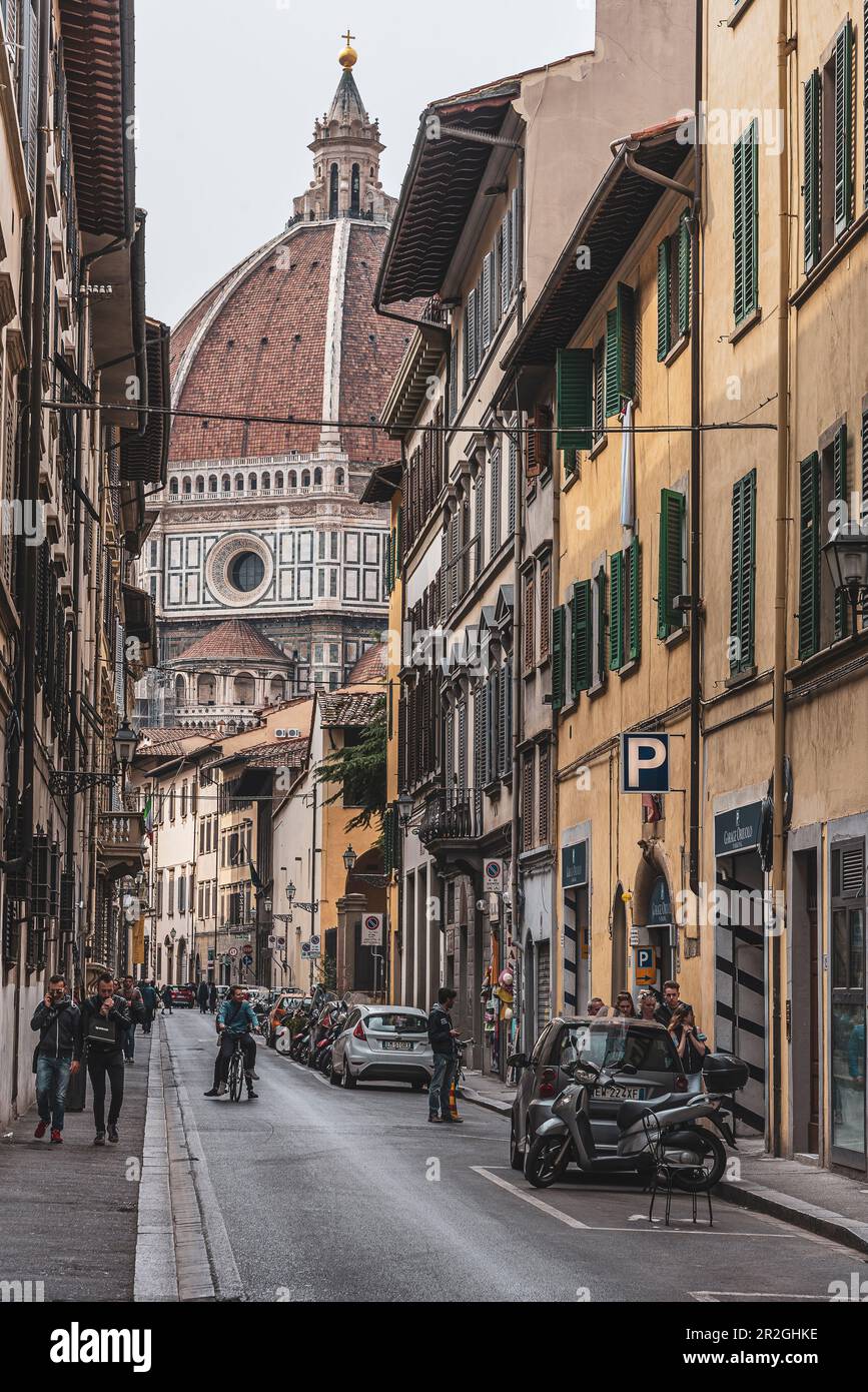 Ciclisti in vicolo con Duomo, Cattedrale di Santa Maria del Fiore sullo sfondo, Firenze, Toscana, Italia Foto Stock