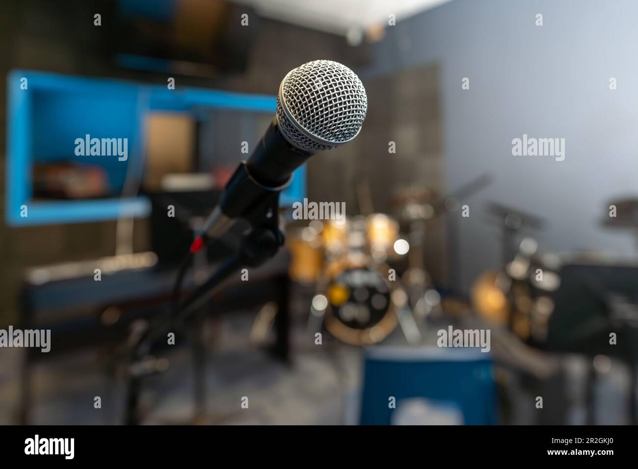 Microfono in uno studio di registrazione con sfondo sfocato, incluso un drum kit. Foto Stock