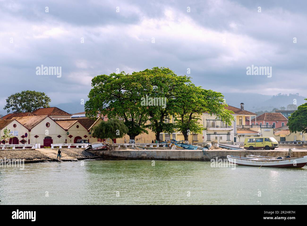 Vecchi magazzini e barche da pesca sotto il cielo nuvoloso scuro a Ana Chavez Bay a Sao Tome sull'isola di Sao Tome in Africa occidentale Foto Stock