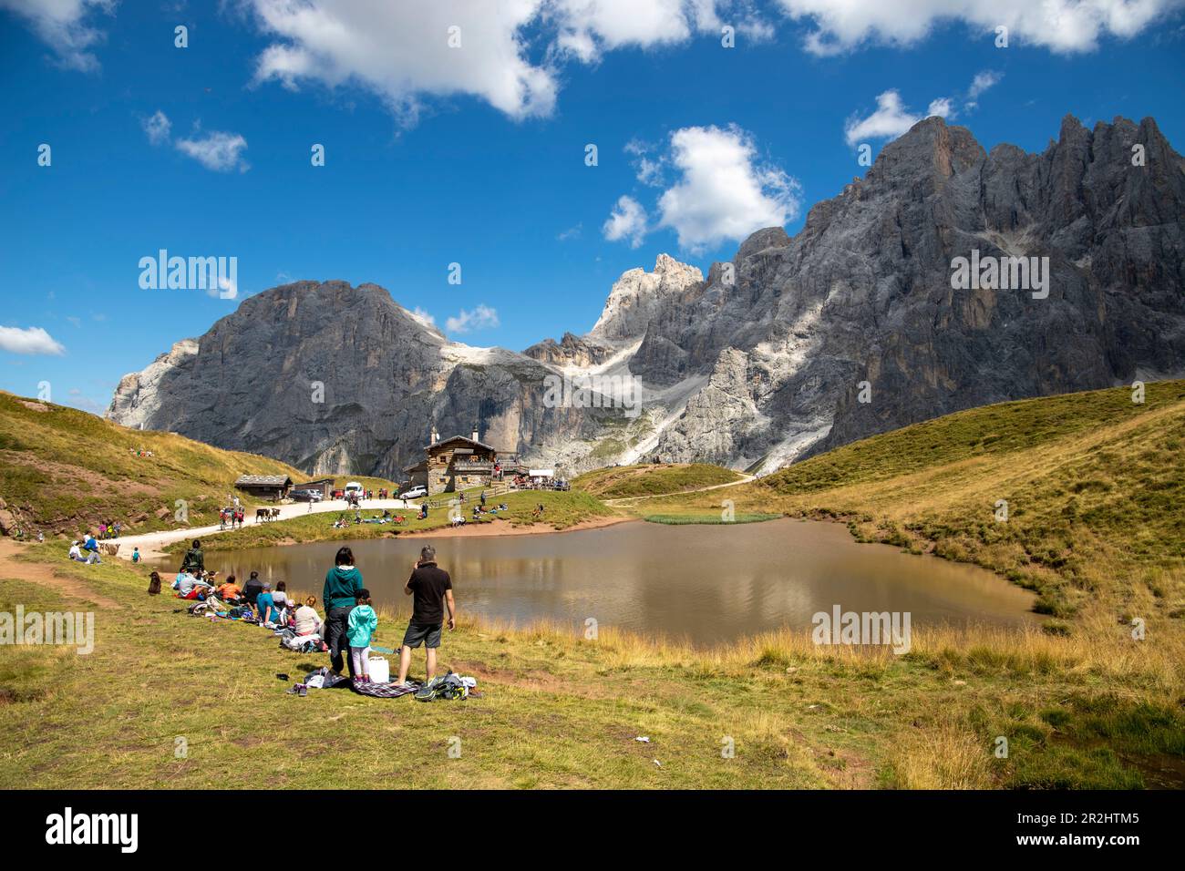 Baita Segantini, turisti intorno ad un piccolo lago. Passo Rolle, Villaggio di San Martino di Castrozza, Trento, Trentino Alto Adige, Italia Foto Stock