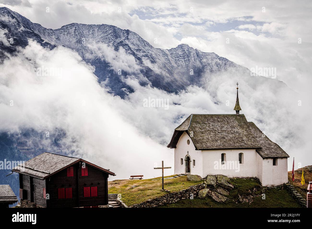 Cielo nebbia sopra la piccola chiesa nel villaggio alpino di Bettmeralp, cantone del Vallese, Svizzera, Europa Foto Stock