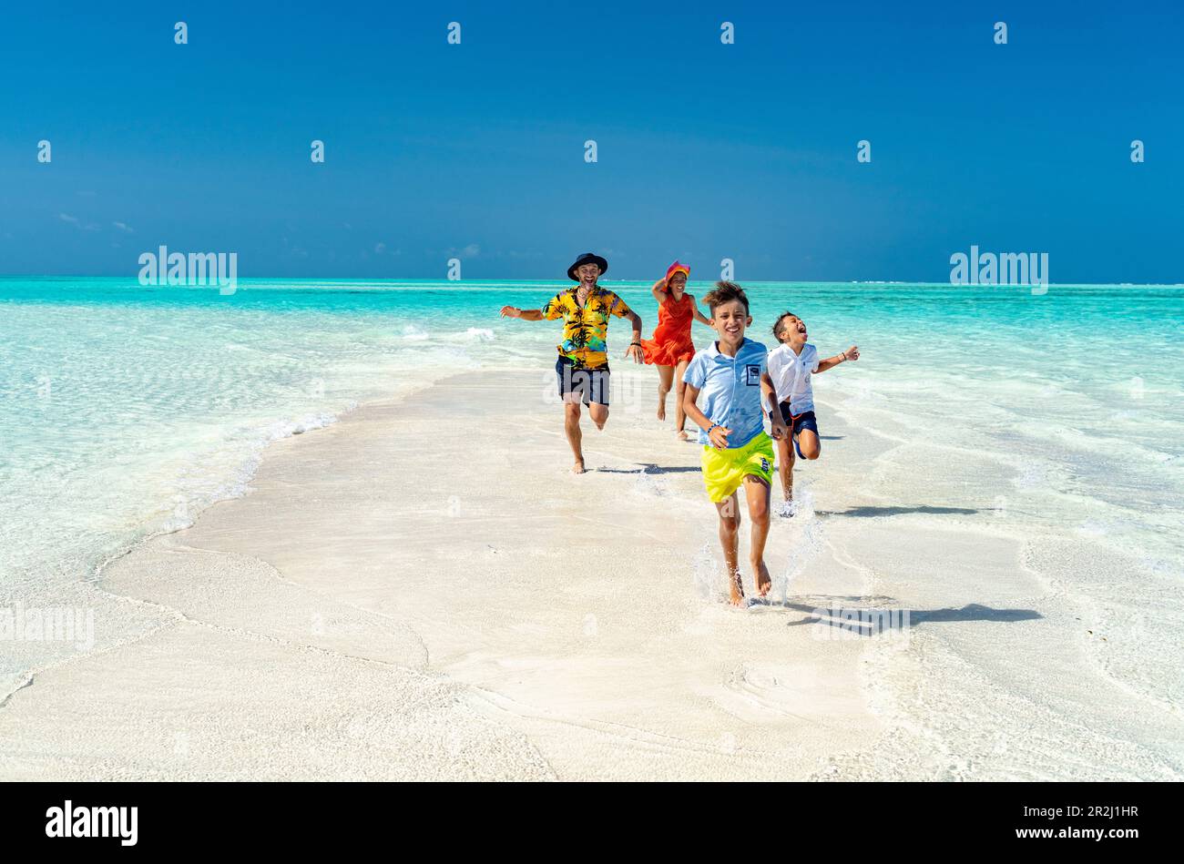 Genitori allegri con figli che si divertono a correre su una spiaggia idilliaca vuota, Zanzibar, Tanzania, Africa orientale, Africa Foto Stock