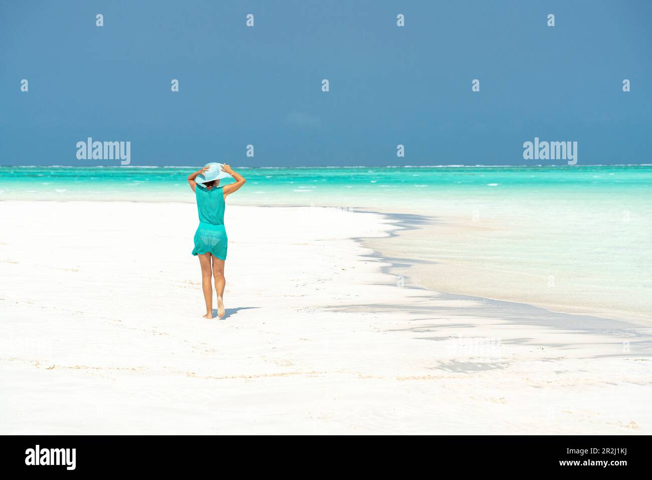 Donna che cammina su idilliaca spiaggia vuota, Zanzibar, Tanzania, Africa orientale, Africa Foto Stock