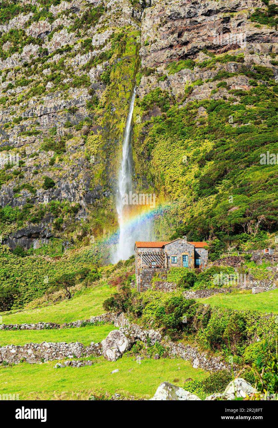 Vista panoramica della cascata di po do Bacalhau caduta behiend una casa con arcobaleno, Faja Grande, Lajes das Flores, Flores Island (Ilha das Flores) Foto Stock