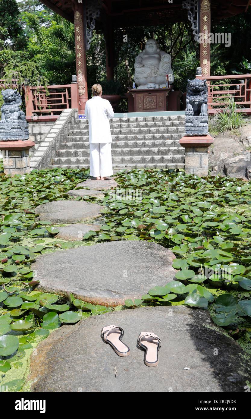 Donna buddista, Phat Quang tempio buddista, tempio stagno con pietre e ninfee d'acqua, Doc, Vietnam, Indocina, Sud-est asiatico, Asia Foto Stock