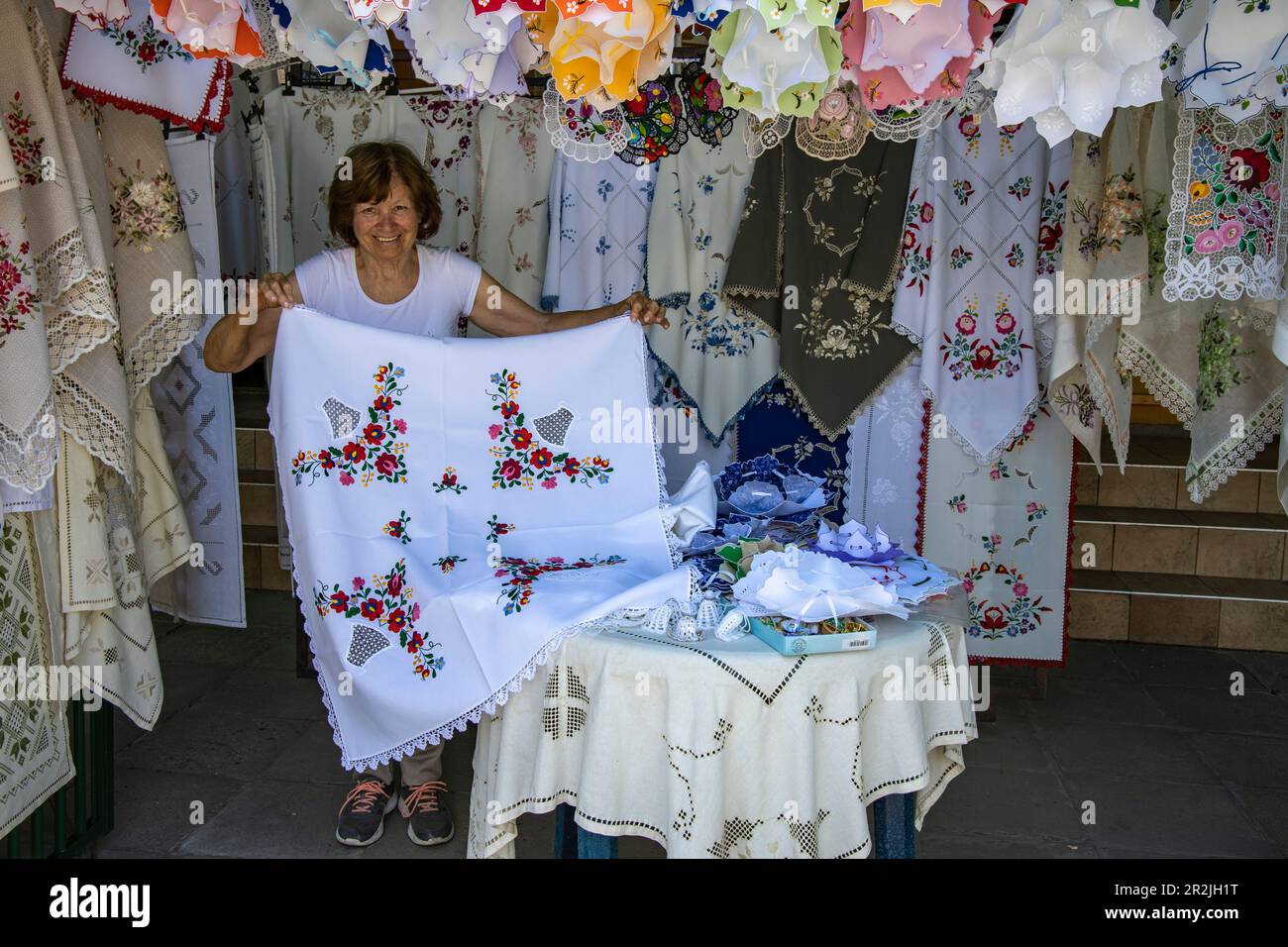 Donna che presenta tovaglia in pizzo lavorato a mano in negozio di maglieria, Szentendre, Pest, Ungheria, Europa Foto Stock