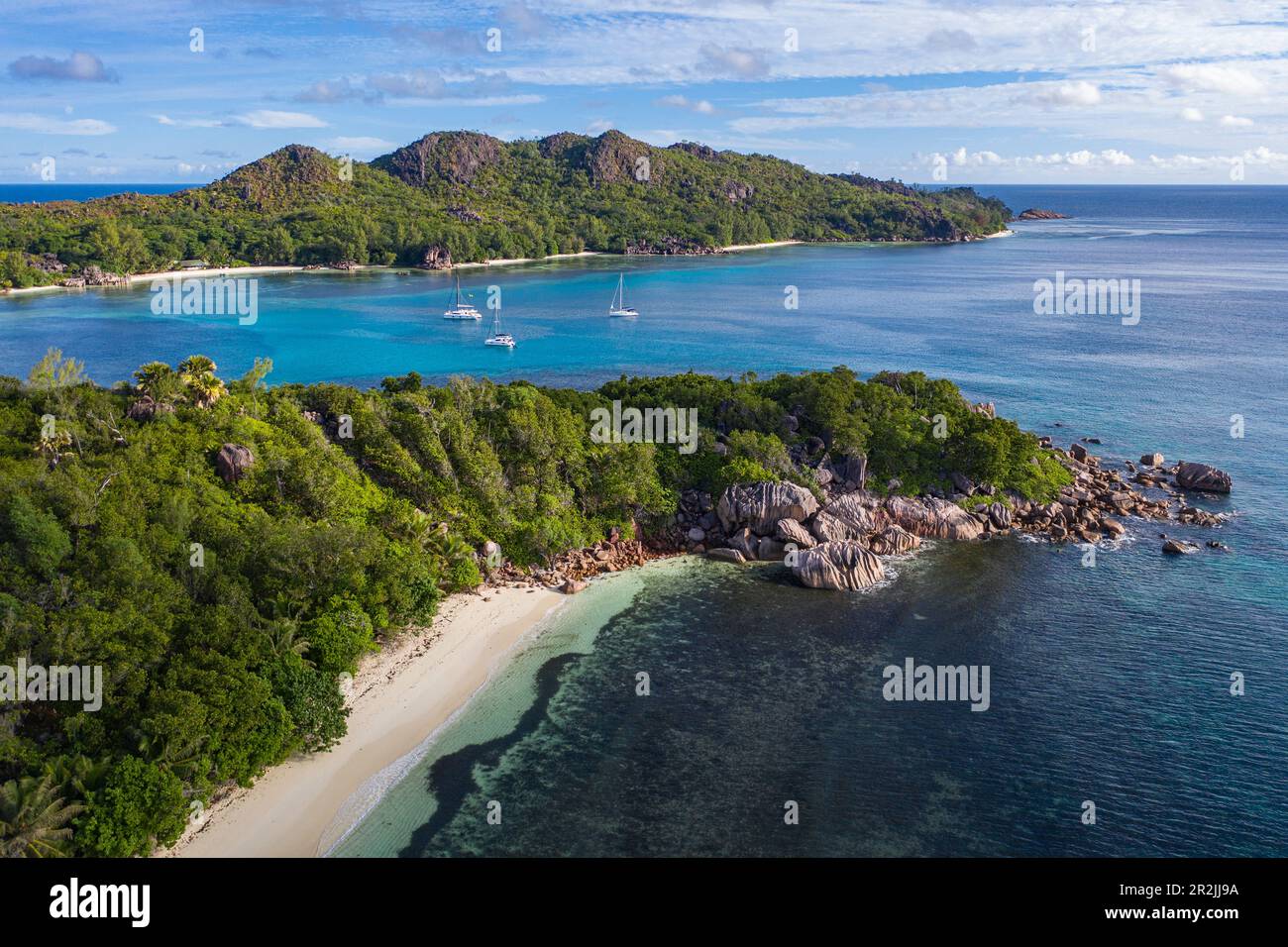Veduta aerea di Anse St. Spiaggia Jose con barche a vela nella baia di Baie Laraie in lontananza, isola di Curieuse, Seychelles, Oceano Indiano Foto Stock