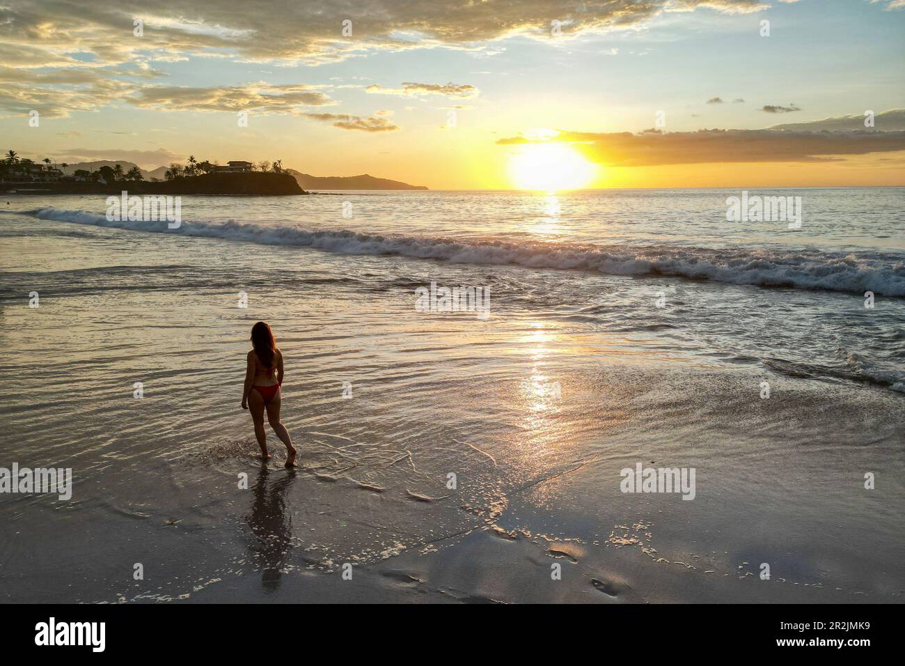 Veduta aerea della donna che cammina sulla spiaggia di Flamingo al tramonto, Playa Flamingo, Guanacaste, Costa Rica, America Centrale Foto Stock