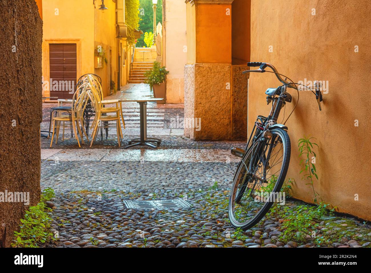 Strada acciottolata medievale con biciclette e palazzi gialli nella città di Verona, Veneto, Italia, vuota strada italiana nel centro storico. Destinazione di viaggio Foto Stock