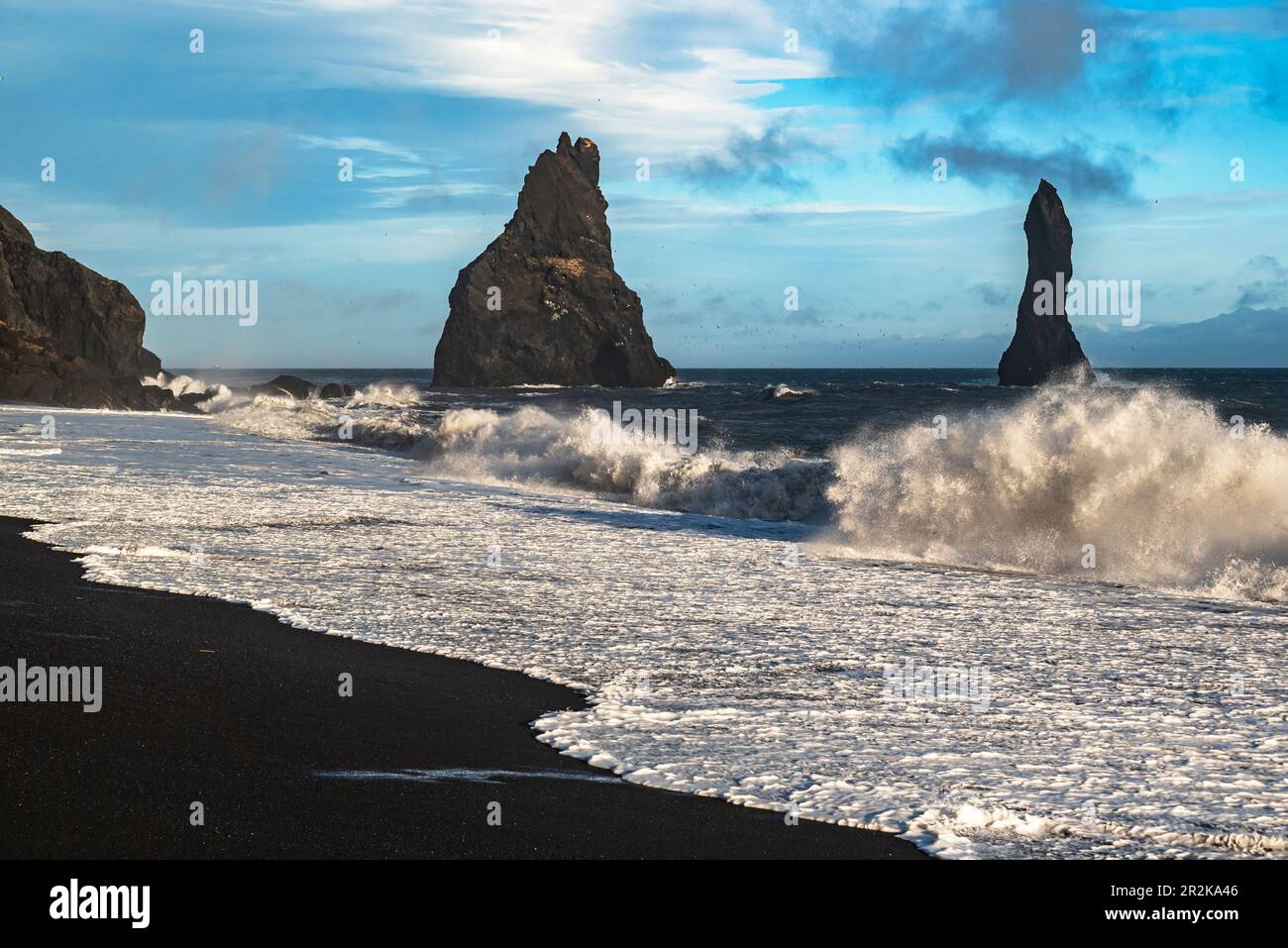 Onde oceaniche possenti che si infrangono contro le pile di basalto mare di Reynisdrangar e sulla sabbia nera della spiaggia di Reynisfjara, vicino a Vík í Mýrdal, Islanda Foto Stock