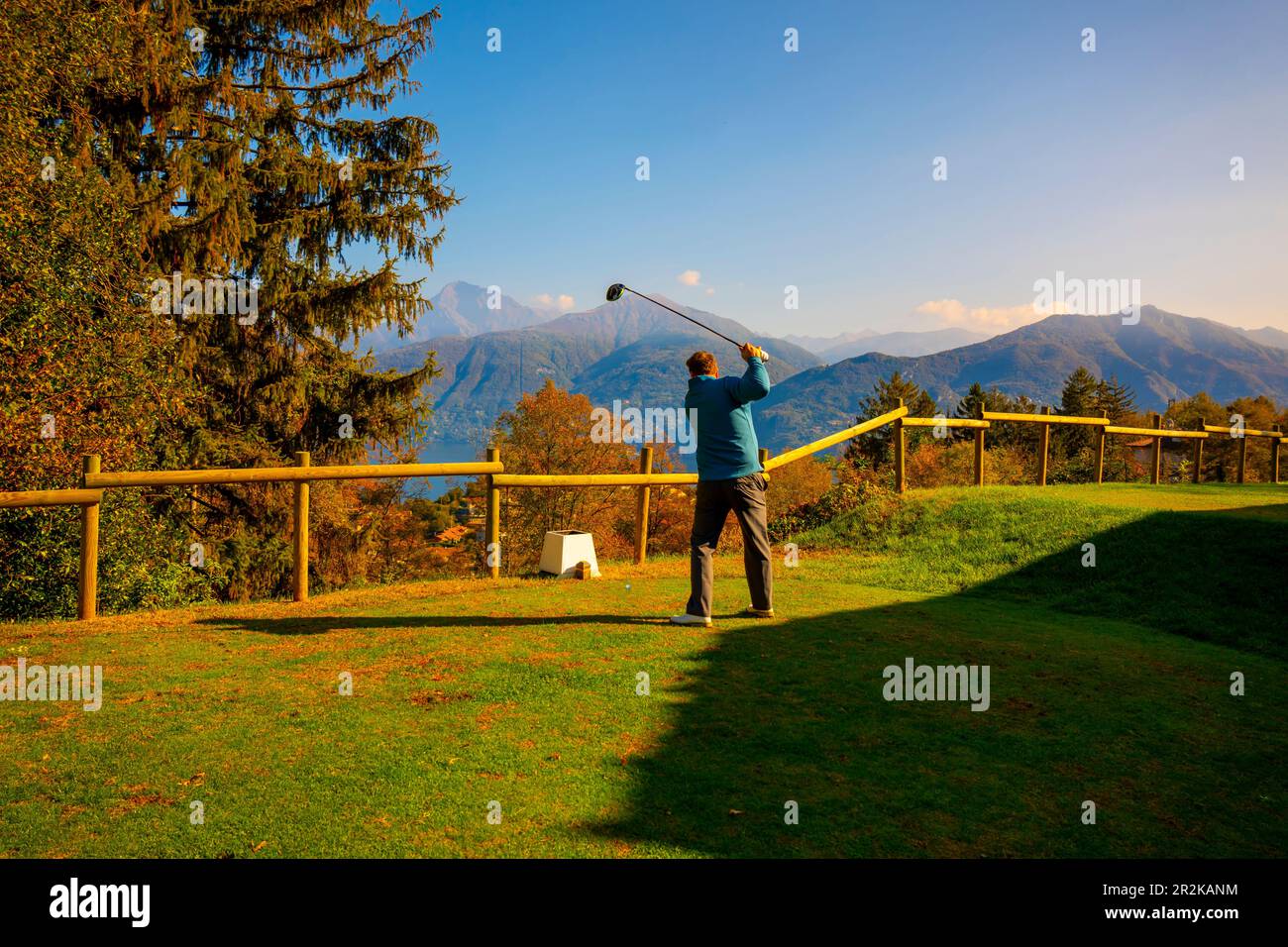 Golf Teeing Off con il suo driver sul campo da golf Menaggio con Mountain View in autunno in Lombardia, Italia. Foto Stock
