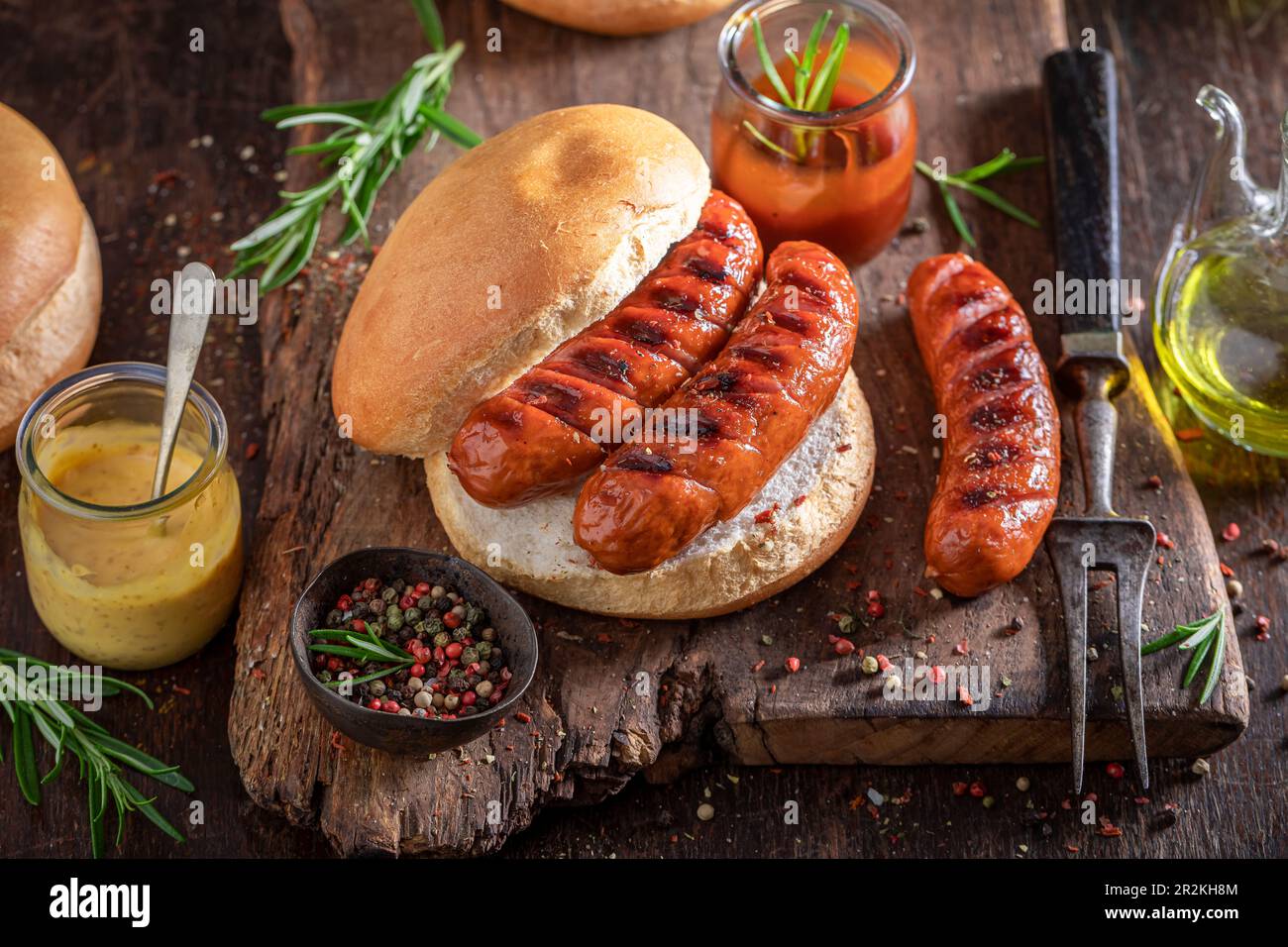 Gustoso panino con salsiccia arrosto, senape e ketchup. Sandwich con salsiccia alla griglia. Foto Stock