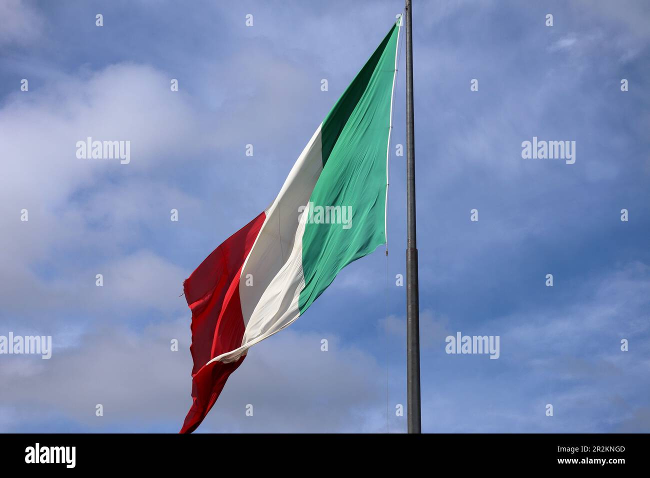 Bandiera dell'Italia che soffia in bright sole mediterraneo su un pennone in piedi in italiano cielo blu Foto Stock