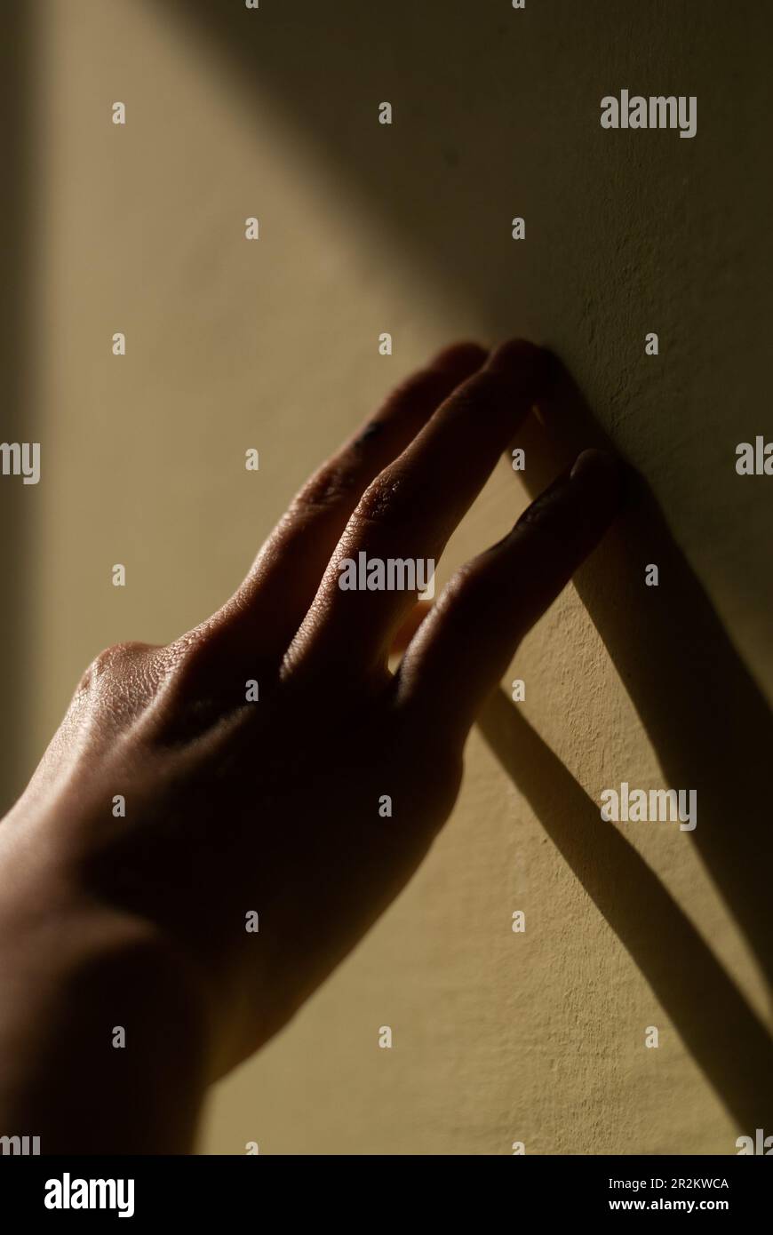 La vista di una mano di una ragazza tocca un muro alla luce del sole del mattino Foto Stock