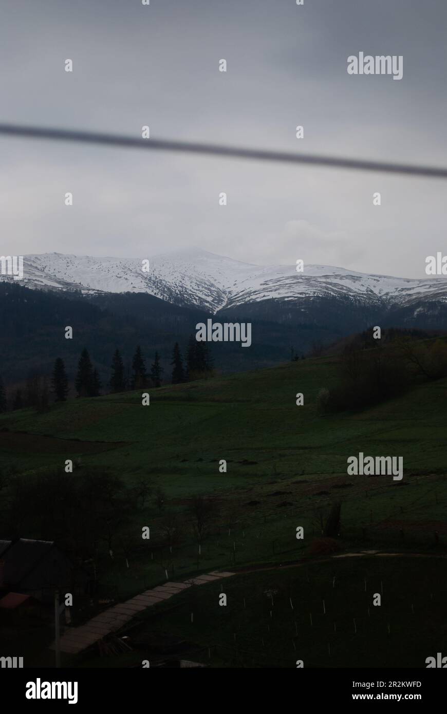 Vista delle verdi colline e delle montagne attraverso la finestra del treno Foto Stock