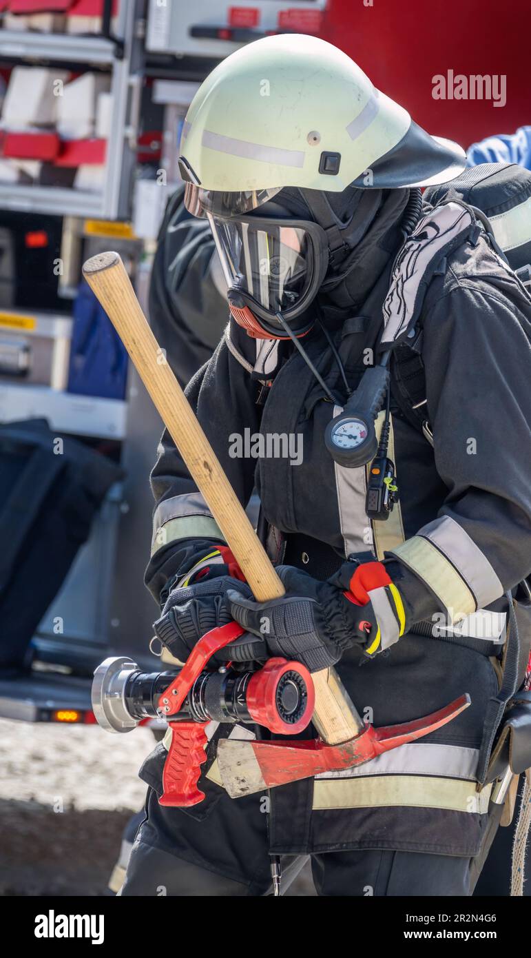 Pompiere in azione con maschera a gas e piccone Foto stock - Alamy