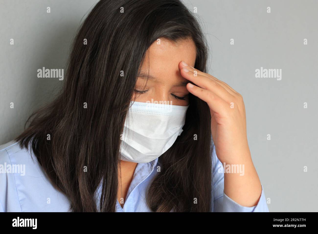 Donna latina con blusa blu e maschera di protezione uso clinico per pandemia covida Foto Stock