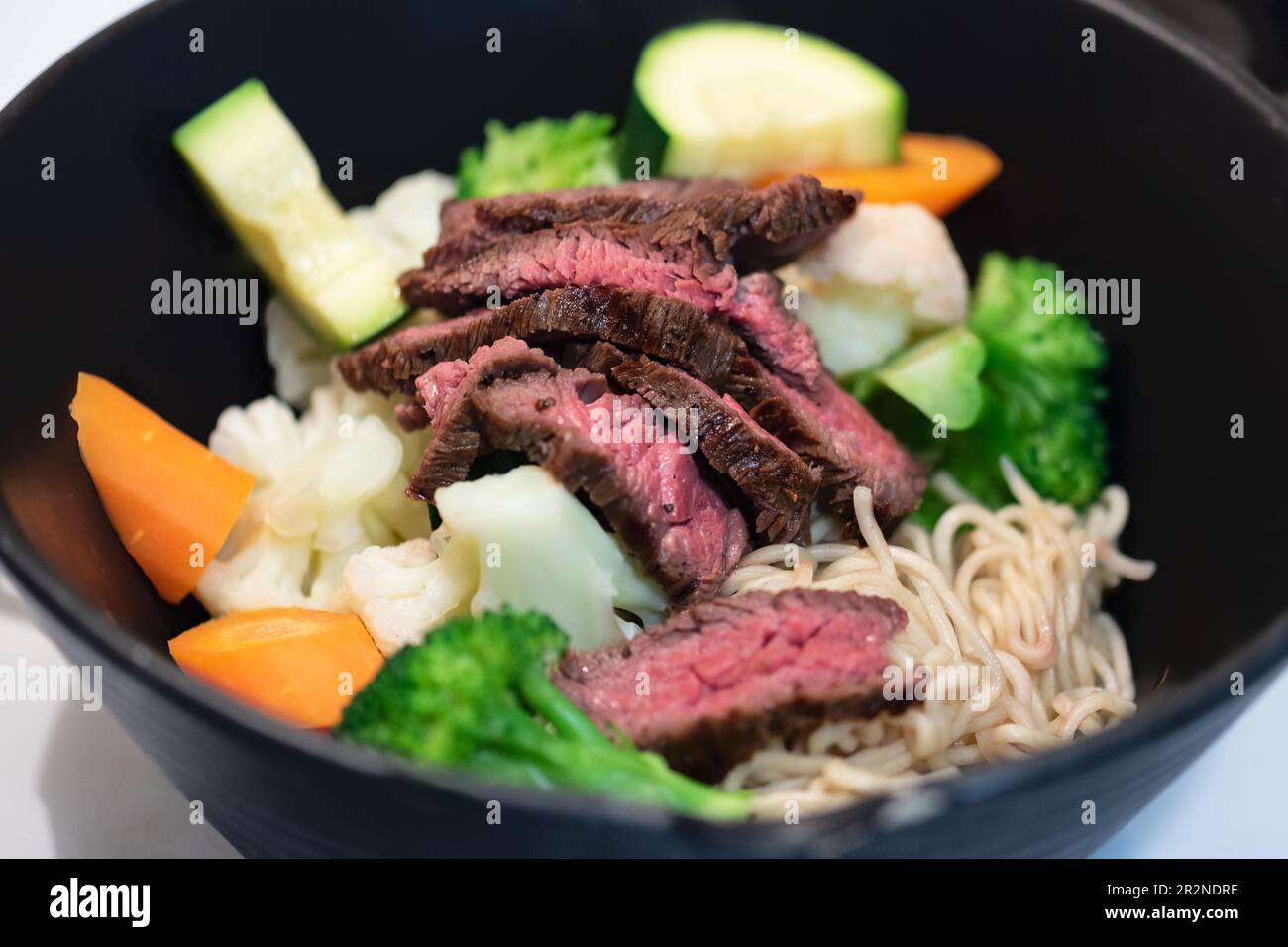 Bistecca di manzo alla griglia e minestra di verdure estive in stile asiatico di Ramen noodle. Foto Stock
