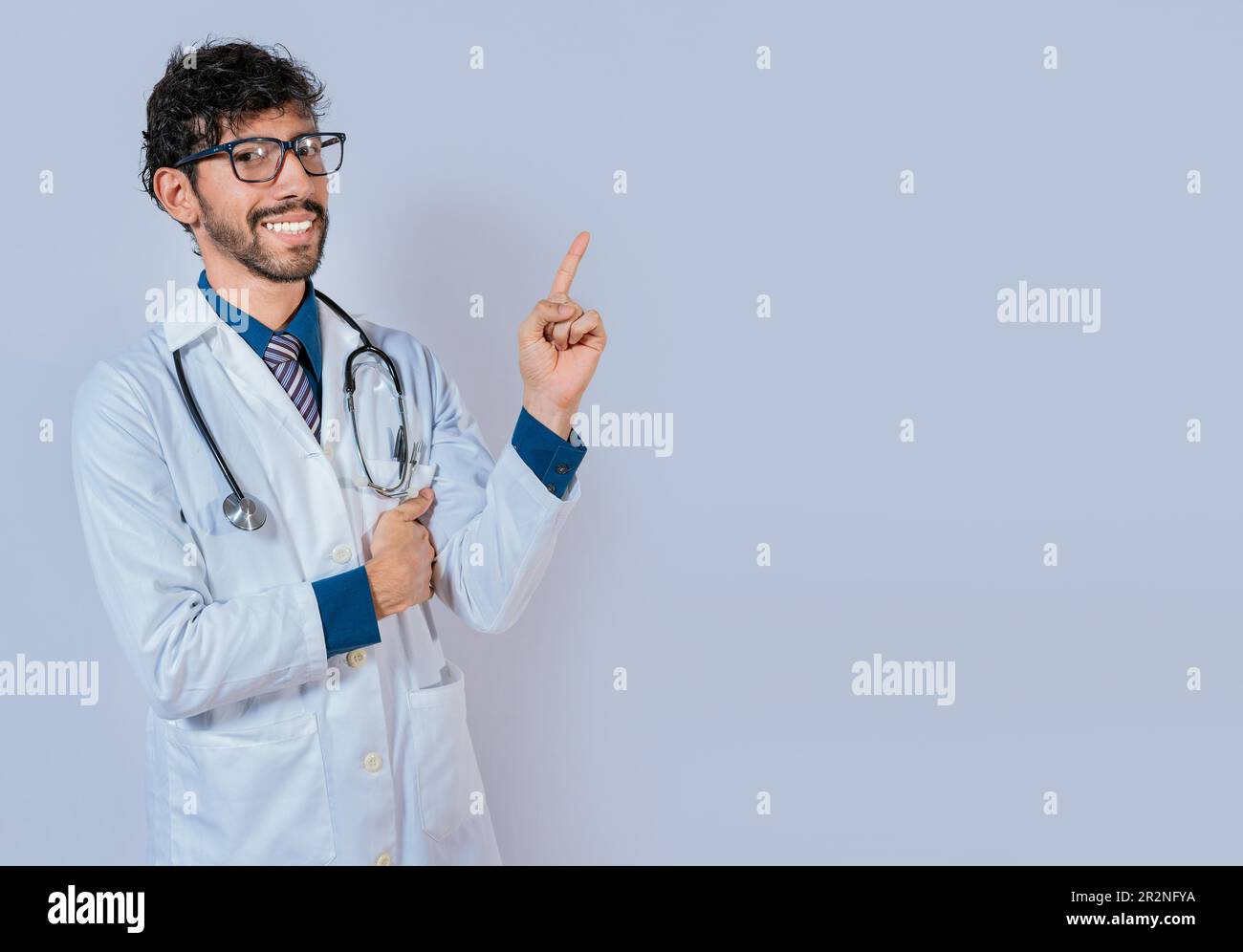 Felice bearded medico che indica lo spazio pubblicitario isolato. Barba medico che indica una promozione con il dito isolato Foto Stock
